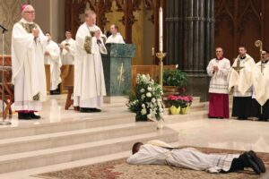 Father Mark Gadoury lays prostrate as the bishop and all gathered pray the Litany of the Saints earlier in the Mass. PHOTO: RICK SNIZEK